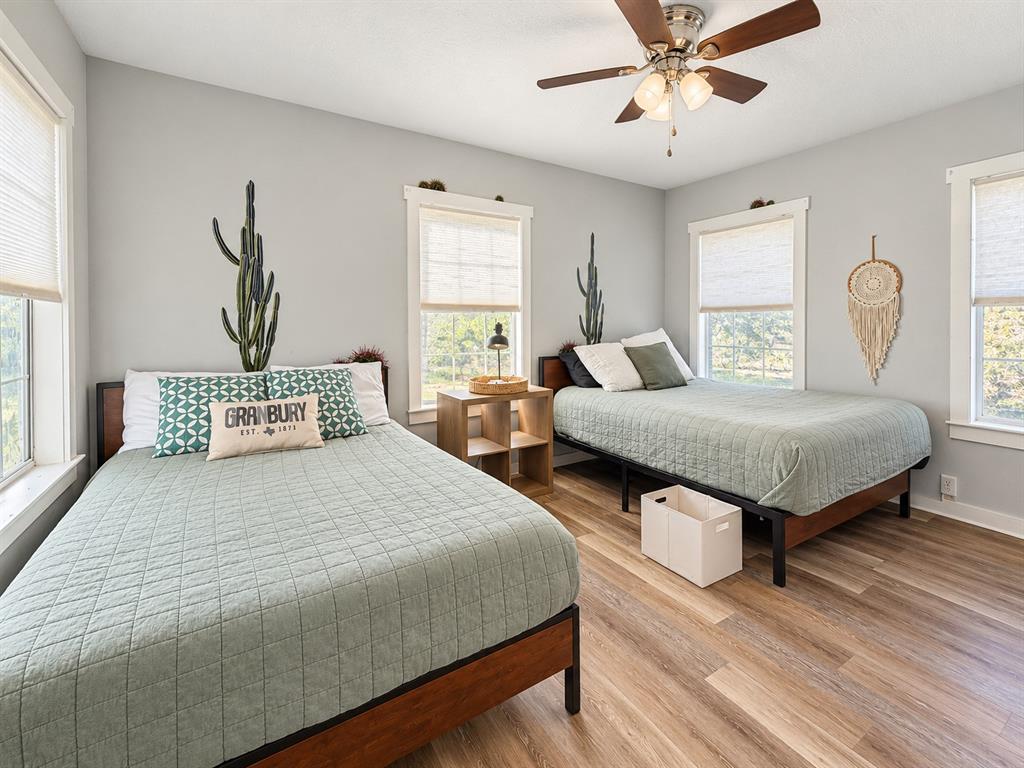 Neutral-toned walls, wood-finish flooring, multi-light ceiling fan, and large windows with integrated blinds