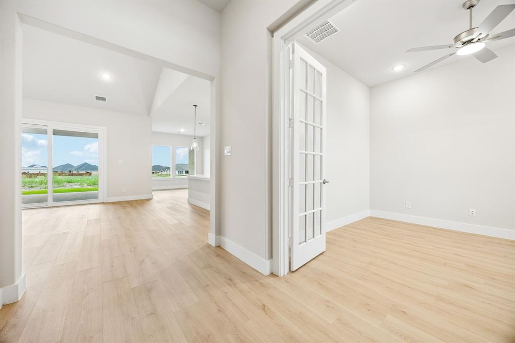 Wood-finish flooring throughout, French doors with glass panes, ceiling-mounted fan with light fixture, and floor-to-ceiling sliding glass doors