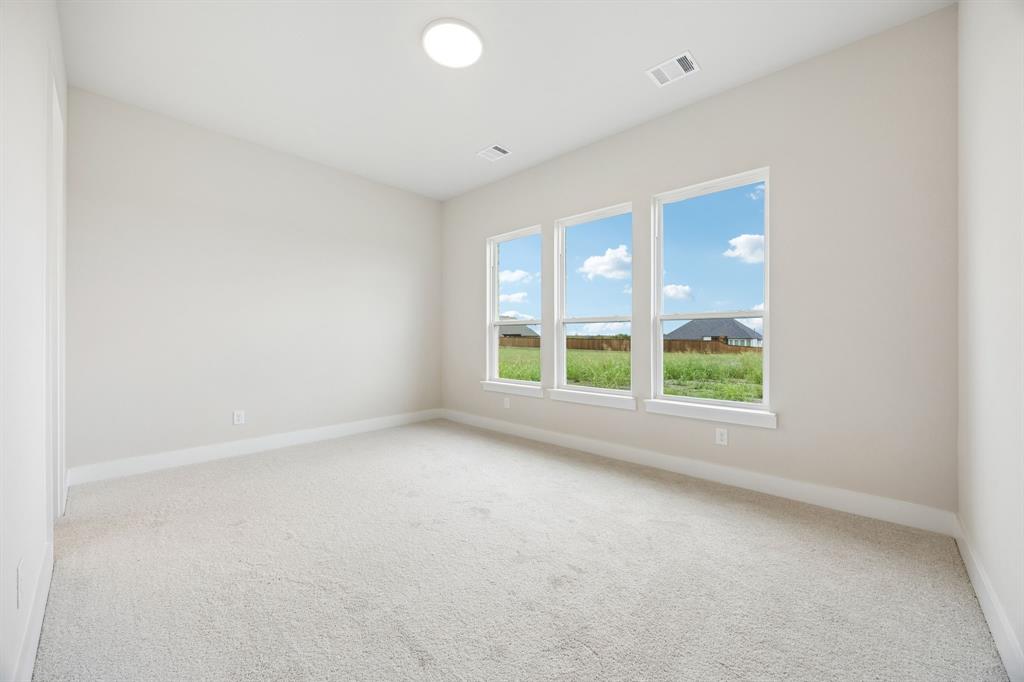 Neutral-toned interior featuring wall-to-wall carpeting, three windows with exterior landscape exposures, and a recessed ceiling light fixture