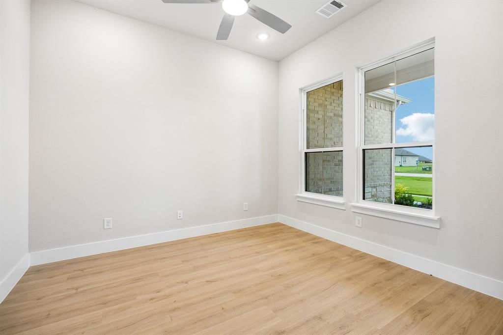 Neutral-toned room featuring wood-finish flooring, dual-pane windows, and a ceiling-mounted fan with integrated light