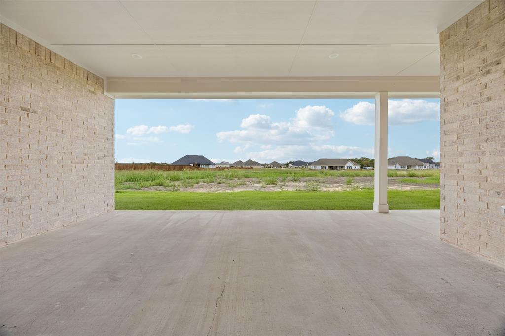Covered patio featuring concrete flooring, brick exterior walls, and a recessed ceiling with integrated lighting