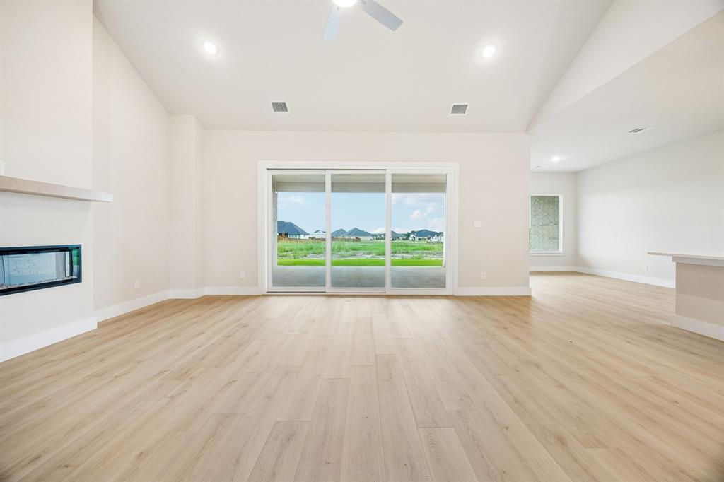Vaulted ceilings, wood-finish flooring, built-in horizontal fireplace, recessed lighting, and sliding glass doors with exterior landscape exposure