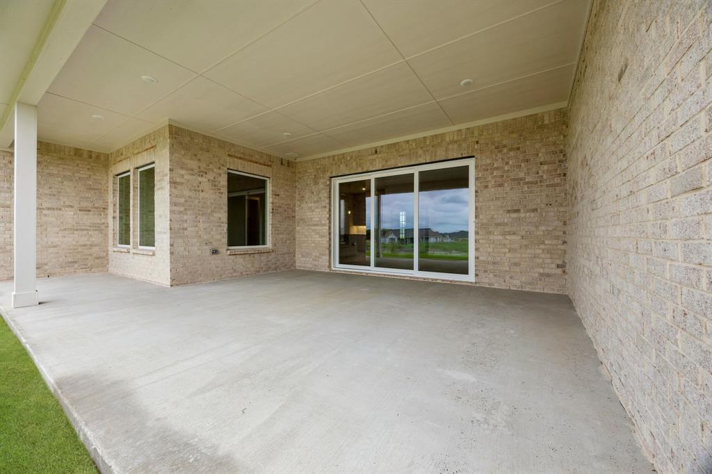 Covered patio featuring a concrete floor, light-colored brick exterior walls, recessed ceiling lighting, and sliding glass doors