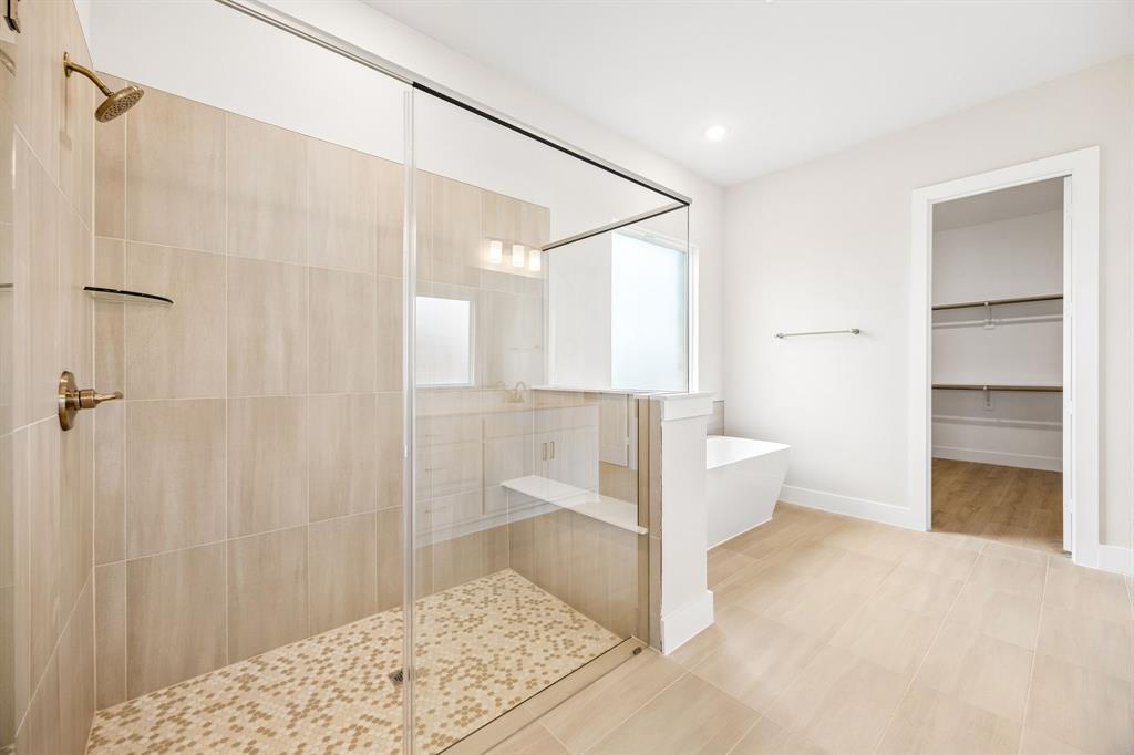Walk-in shower with floor-to-ceiling tile, frameless glass enclosure, built-in tiled bench, and gold-finish fixtures