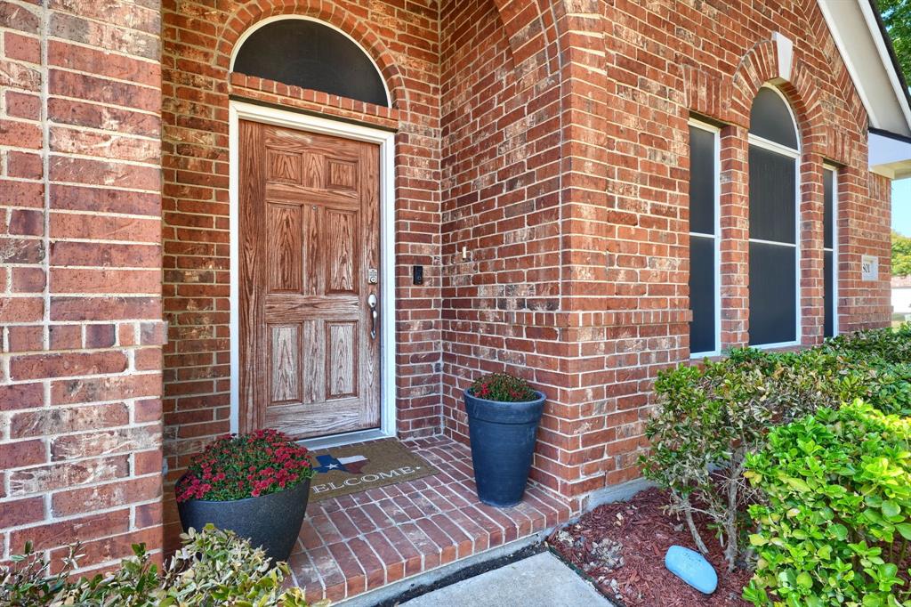 Red brick exterior featuring an arched entryway, a paneled wood-finish door with an arched transom window, and tall arched windows Red brick exterior featuring an arched entryway, a paneled wood-finish door with an arched transom window, and tall arched windows