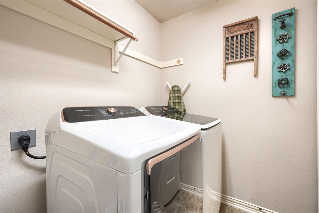 Laundry area featuring top-load Samsung appliances and a mounted wall shelf