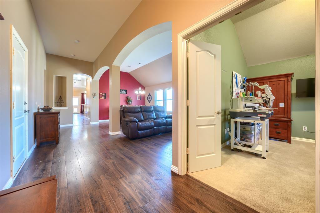 Interior hallway featuring wood-finish flooring, vaulted ceilings, and architectural archways Interior hallway featuring wood-finish flooring, vaulted ceilings, and architectural archways