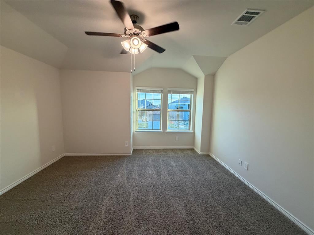 Vaulted ceilings, neutral carpeting, multi-light ceiling fan, and dual-pane windows with grid detailing