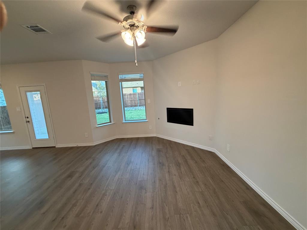 Open interior featuring wood-finish flooring, a recessed fireplace, multi-pane windows, and a ceiling fan with integrated lighting