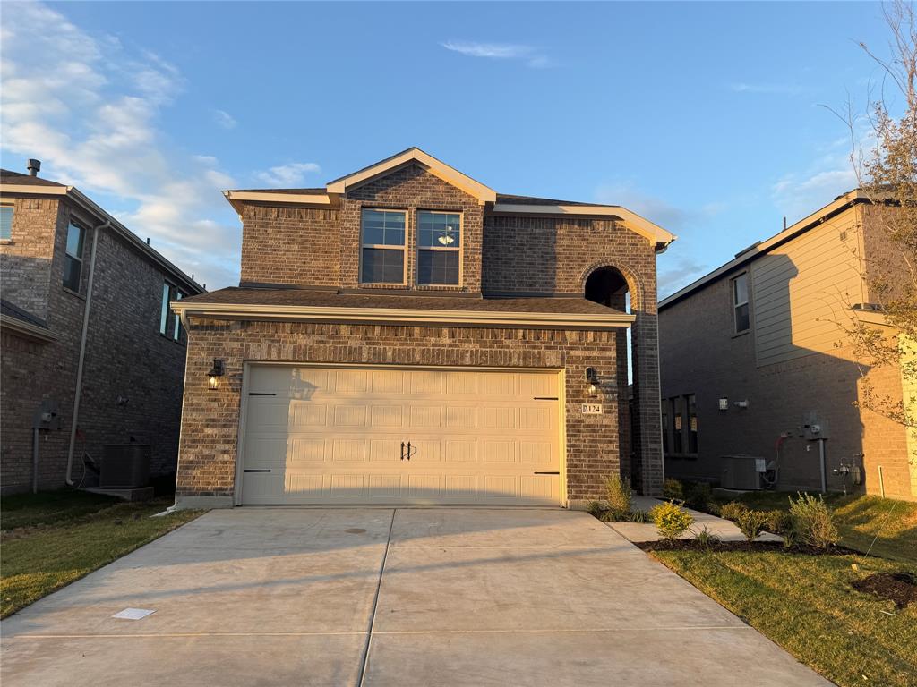 Two-story brick exterior featuring a multi-gabled roofline, concrete driveway, and attached two-car garage