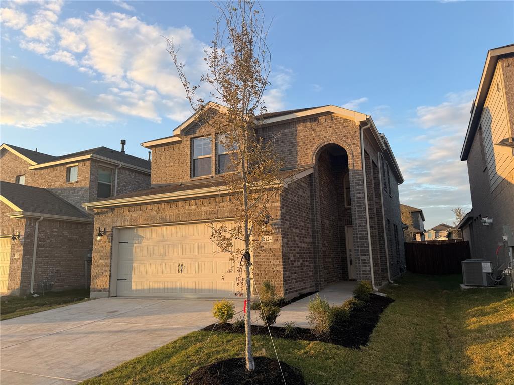 Two-story brick exterior featuring an arched entryway, two-car garage, and concrete driveway