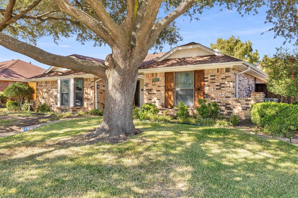 Single-story brick exterior featuring wooden shutters, a multi-gabled roofline, and a mature shade tree on a grass lawn
