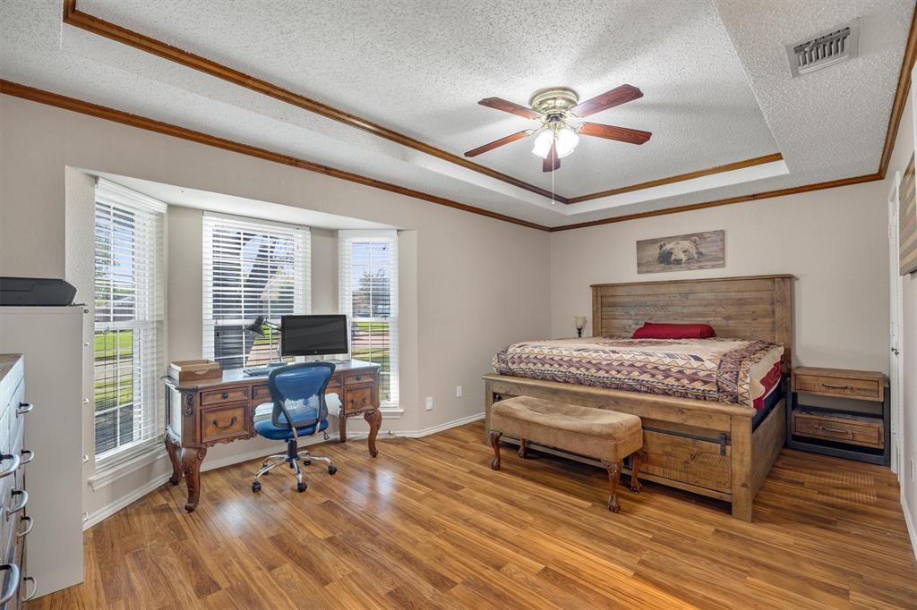 Tray ceiling with decorative wood trim, bay window, and wood-finish flooring