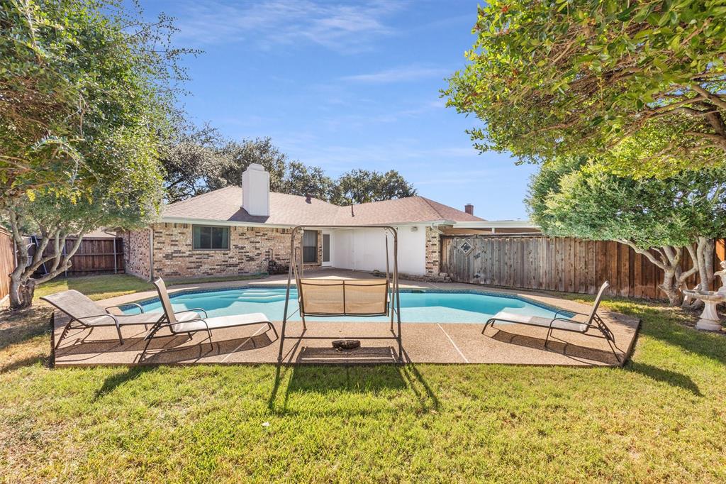 Private backyard featuring an in-ground swimming pool, concrete decking, mature trees, and wood perimeter fencing