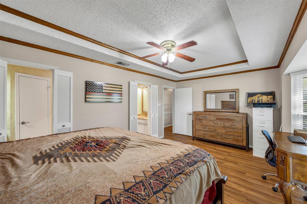 Tray ceiling with wood-trim detailing, wood-finish flooring, and ceiling fan with integrated lighting