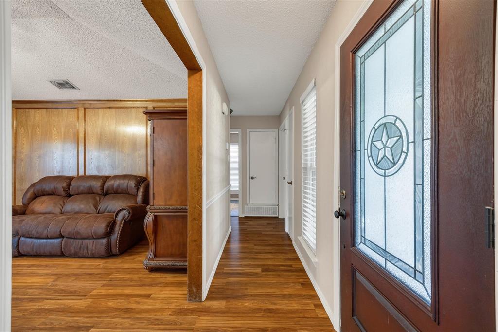 Entryway featuring a dark wood-finish door with decorative leaded glass paneling, wood-finish flooring, wood-paneled walls, and chair rail molding