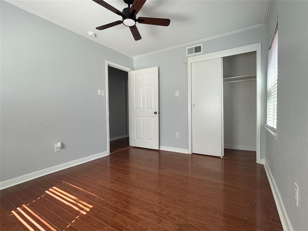 Room featuring wood-finish flooring, a ceiling fan with integrated lighting, a sliding-door closet, and a neutral color palette