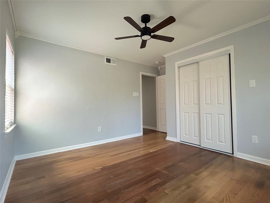 Room featuring wood-finish flooring, a ceiling fan with integrated lighting, and a closet with white paneled sliding doors