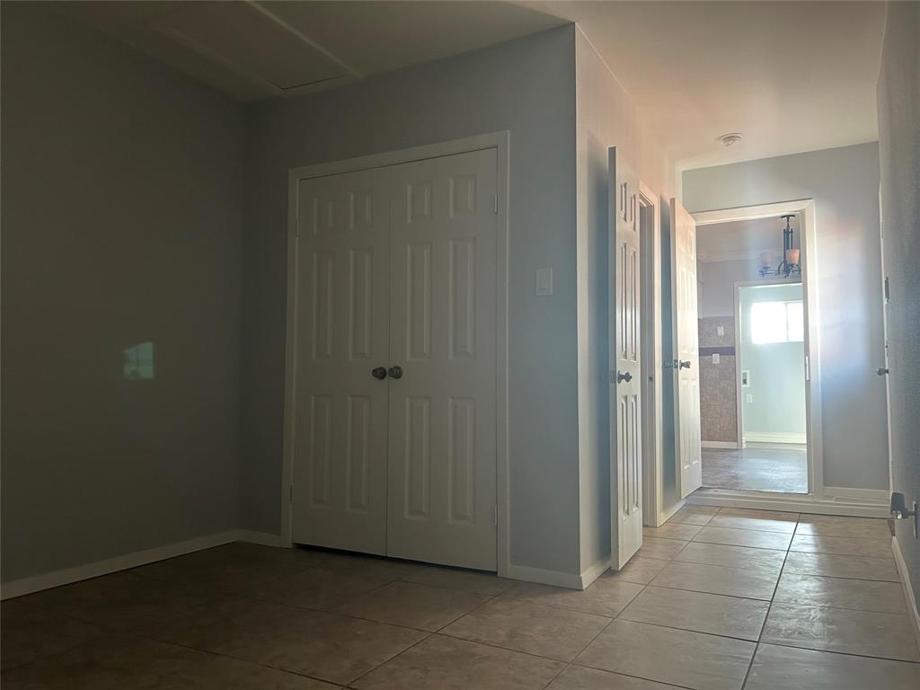 Neutral-toned wall paint, ceramic tile flooring, and white paneled interior doors featuring brushed metal hardware
