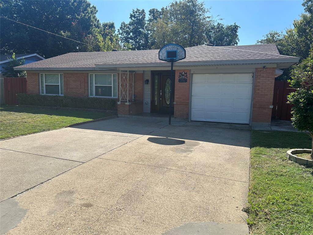 Single-story brick exterior featuring a shingled roof, an attached garage, and a concrete driveway Single-story brick exterior featuring a shingled roof, an attached garage, and a concrete driveway