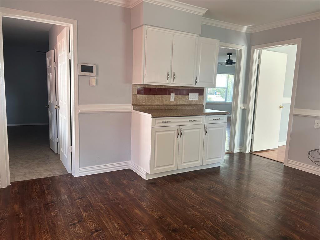 White cabinetry with brushed nickel hardware, stone-finish countertops, tiled backsplash, and dark wood-finish flooring White cabinetry with brushed nickel hardware, stone-finish countertops, tiled backsplash, and dark wood-finish flooring