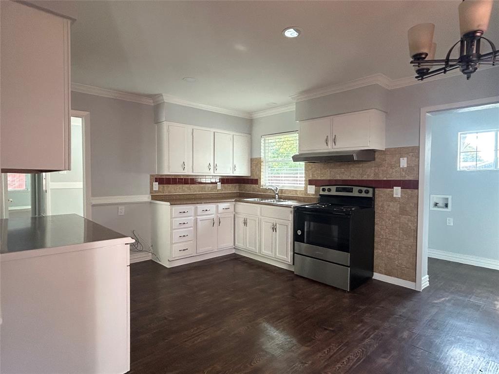 Kitchen featuring white cabinetry, wood-finish flooring, a stainless steel range, a dual-basin sink, and a decorative tile backsplash Kitchen featuring white cabinetry, wood-finish flooring, a stainless steel range, a dual-basin sink, and a decorative tile backsplash