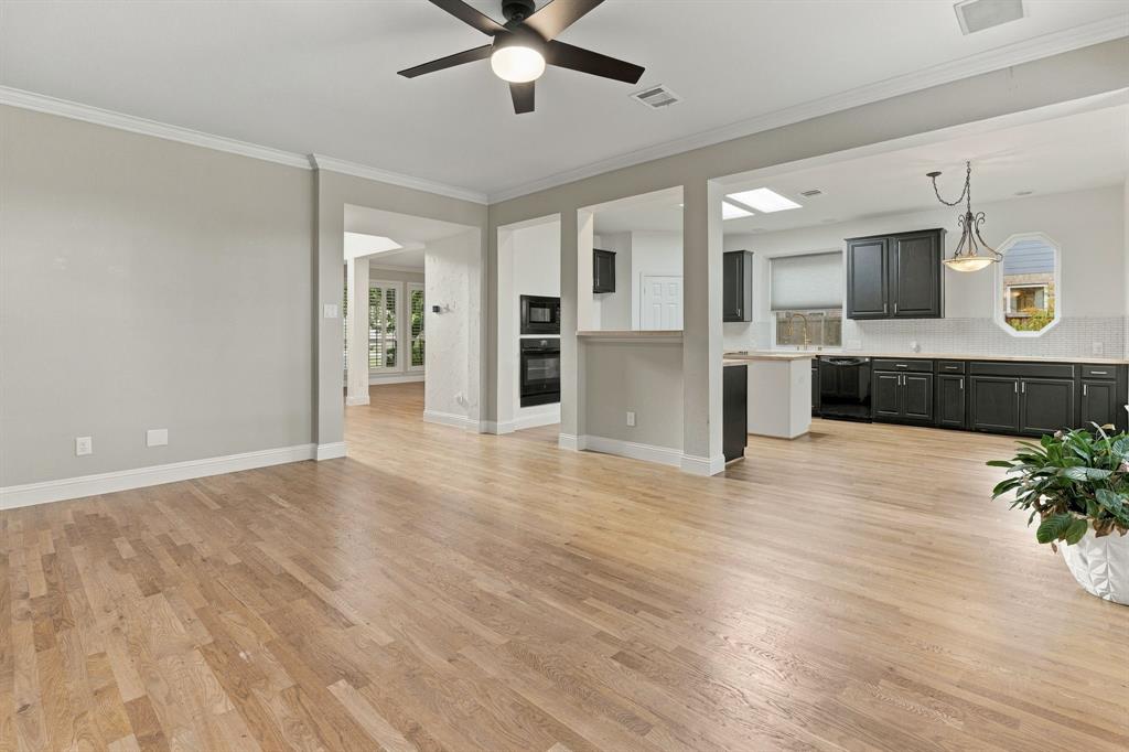Open-concept area featuring wood-finish flooring, a matte black ceiling fan, recessed lighting, and kitchen cabinetry with dark finishes