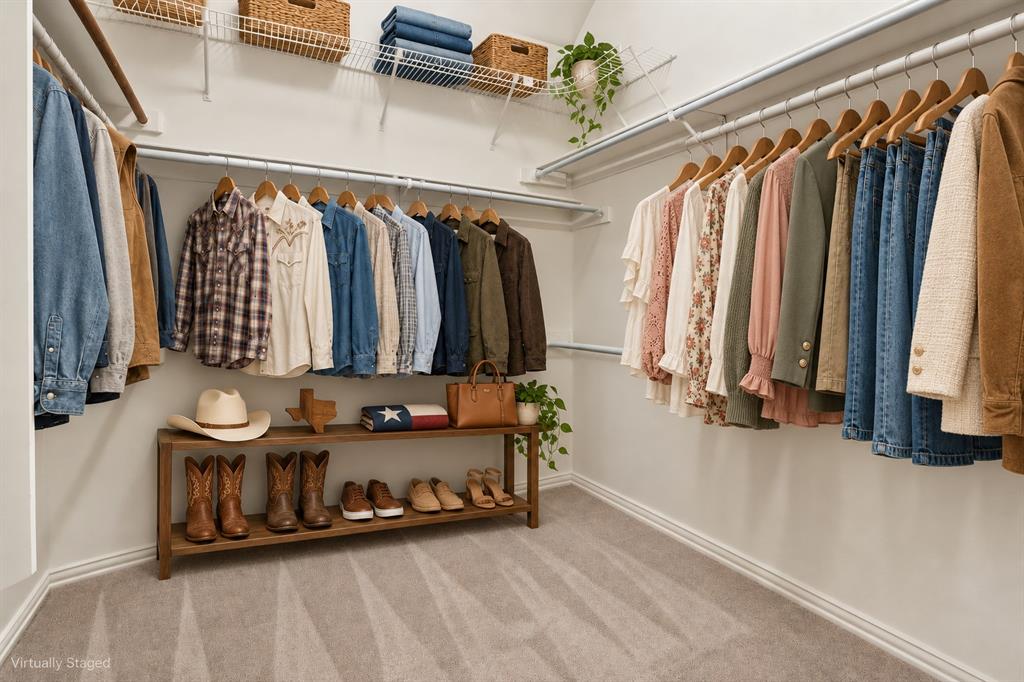 Walk-in closet featuring tiered wire shelving, dual-level hanging rods, and neutral carpeting