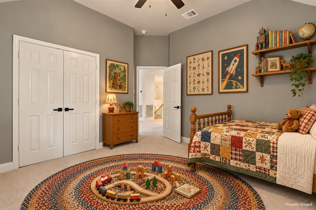 Vaulted ceilings, neutral wall color, carpeted flooring, double-door closet with matte black hardware, and an attached ceiling fan