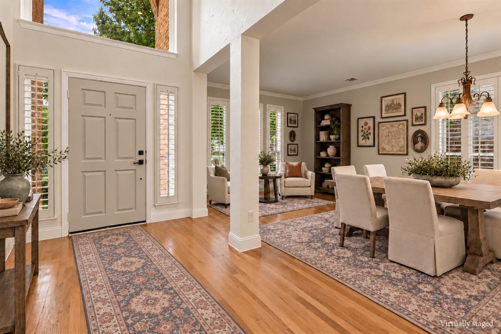 Entryway featuring double-height ceilings, wood-finish flooring, plantation shutters, and a multi-light chandelier