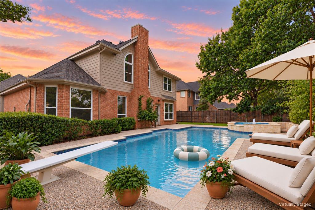 Brick and horizontal siding exterior featuring a multi-story chimney, a swimming pool with a diving board, and an integrated spa