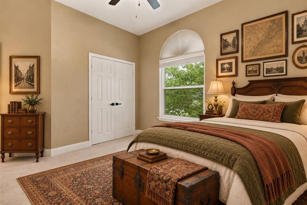 Neutral wall tones, arched window with a fanlight header, ceiling fan, and double-door closet