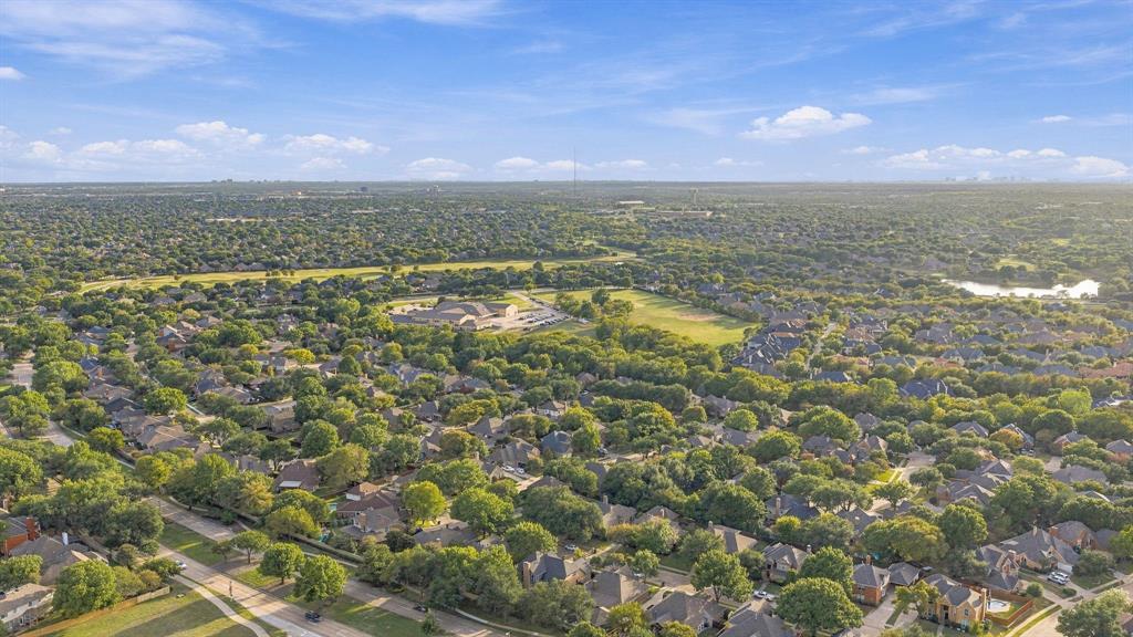 Aerial perspective featuring mature tree canopies, expansive green space, and residential surroundings
