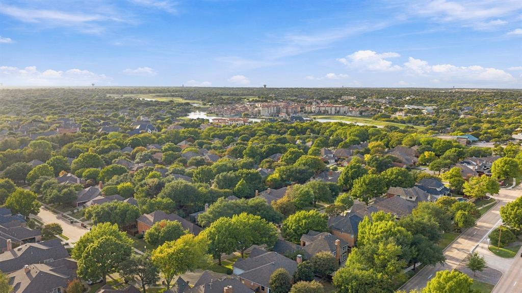 Aerial perspective of a residential neighborhood characterized by dense mature tree coverage and established landscaping