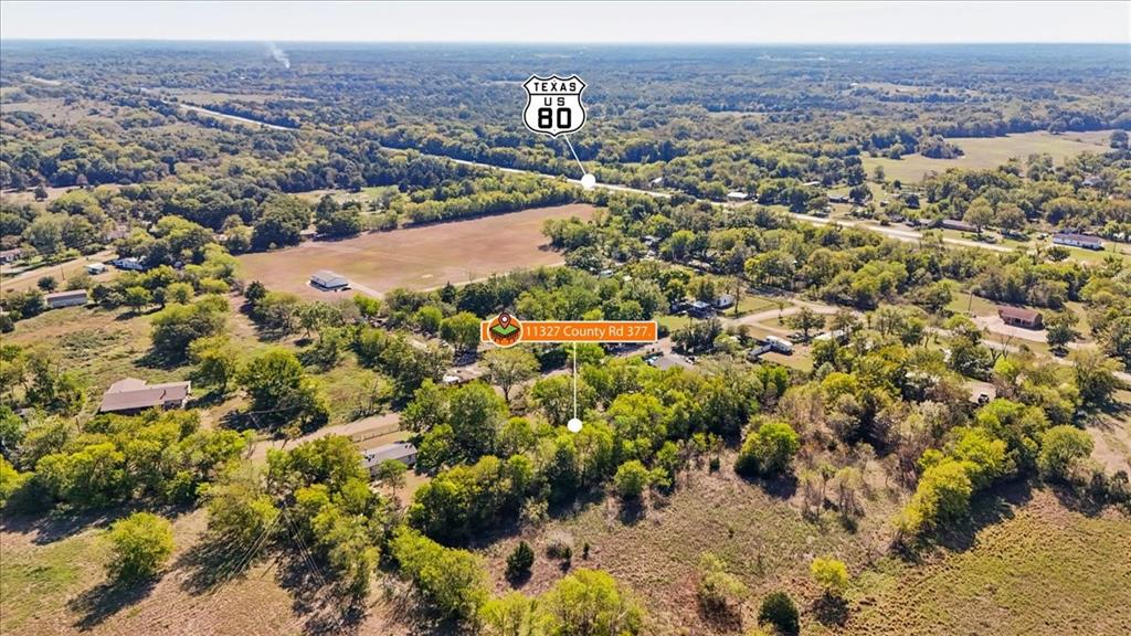 Aerial view of expansive acreage featuring mature trees, open pastureland, and established perimeter vegetation Aerial view of expansive acreage featuring mature trees, open pastureland, and established perimeter vegetation
