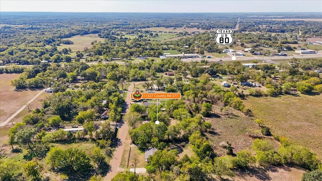 Aerial perspective of a multi-acre property featuring mature tree clusters, open pasture land, and established road access near US-80 Aerial perspective of a multi-acre property featuring mature tree clusters, open pasture land, and established road access near US-80