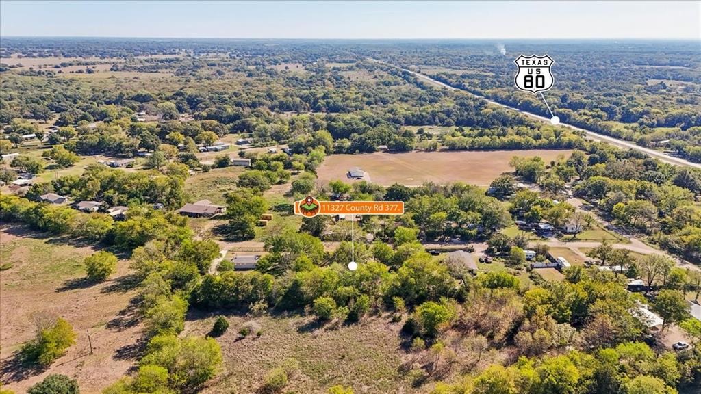 Aerial perspective of expansive acreage featuring mature tree clusters, open pasture land, and defined property boundaries Aerial perspective of expansive acreage featuring mature tree clusters, open pasture land, and defined property boundaries