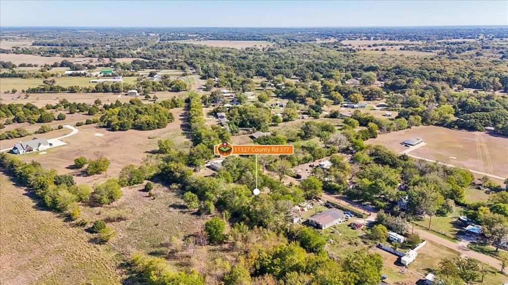 Aerial perspective of expansive acreage featuring mature trees, open pastureland, and established rural surroundings Aerial perspective of expansive acreage featuring mature trees, open pastureland, and established rural surroundings