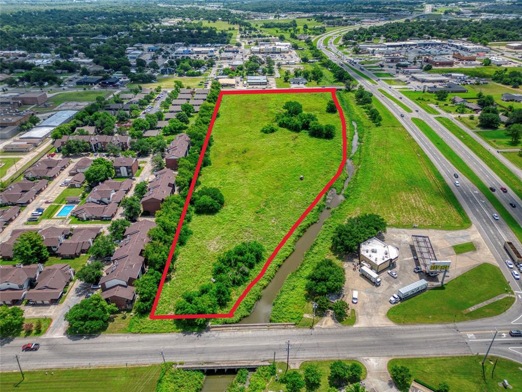 Undeveloped land parcel featuring expansive open terrain, mature trees, and frontage along a natural water feature