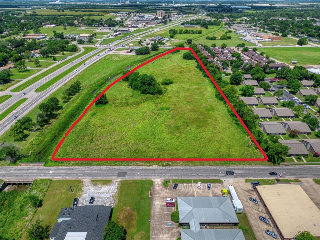 Expansive parcel of land featuring open green space, mature trees, and direct roadway access