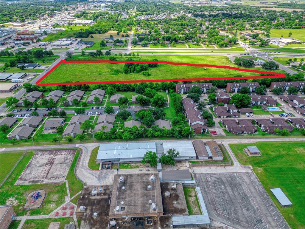 Expansive vacant land parcel featuring significant street frontage, level topography, and established clusters of mature trees