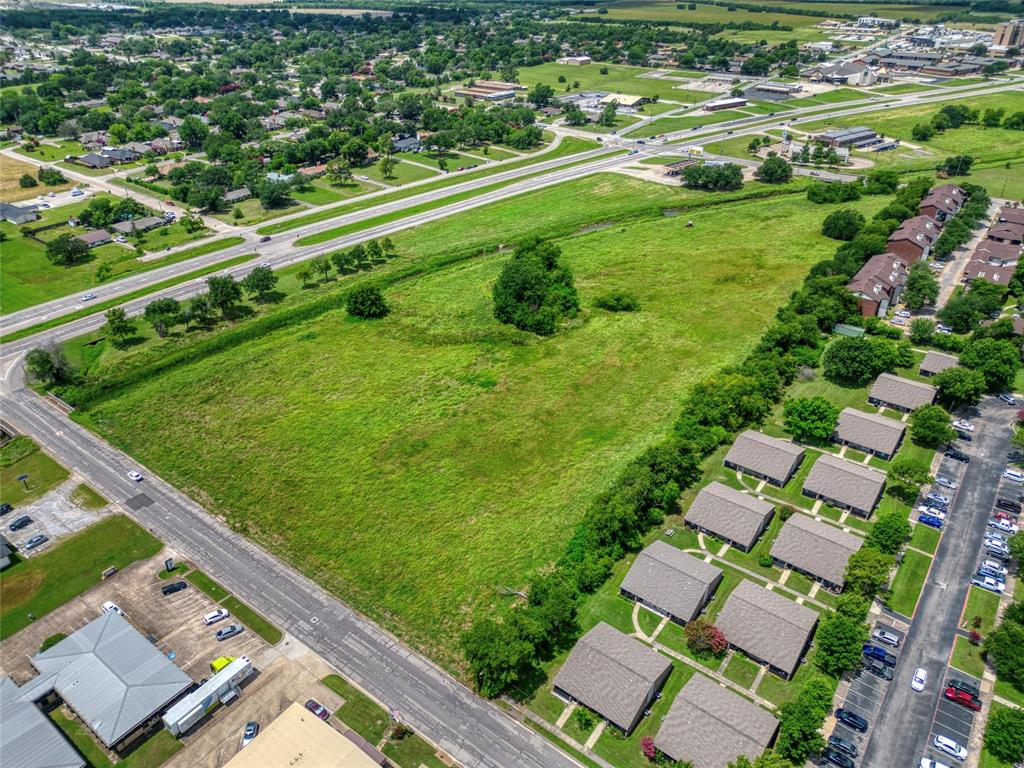 Expansive acreage featuring prominent street frontage, significant open green space, mature tree clusters, and direct access to established thoroughfares