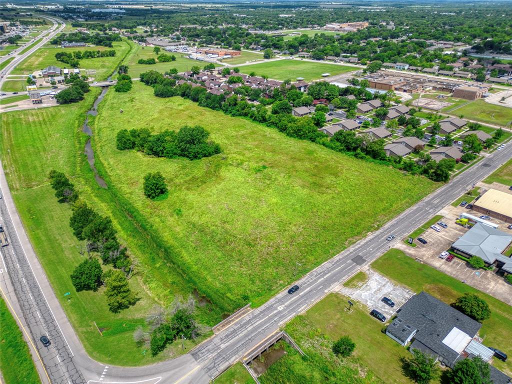 Expansive undeveloped acreage featuring cleared terrain, mature trees, and natural drainage topography with direct frontage to paved thoroughfares