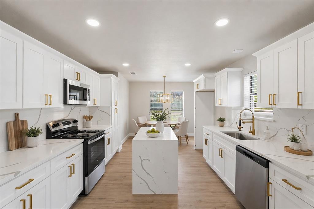 Kitchen featuring white cabinetry with brass-finish hardware, stone-patterned countertops, a central island, recessed lighting, and wood-finish flooring Kitchen featuring white cabinetry with brass-finish hardware, stone-patterned countertops, a central island, recessed lighting, and wood-finish flooring
