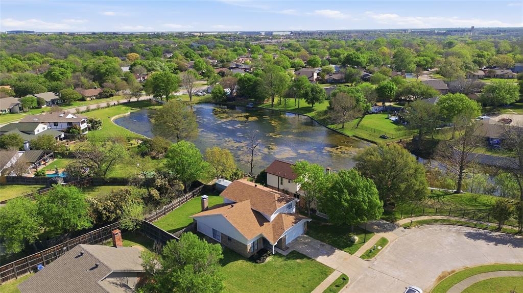 Aerial perspective featuring a multi-story residence with a shingled roof, attached garage, and a fenced backyard