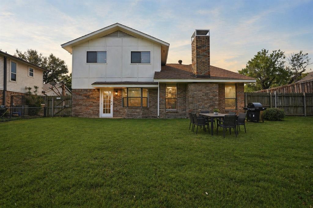 Two-story exterior featuring a brick and panel facade, expansive backyard, and a prominent chimney