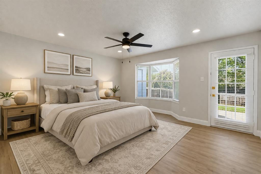 Neutral-toned walls, wood-finish flooring, multi-pane glass door, bay window, and matte black ceiling fan Neutral-toned walls, wood-finish flooring, multi-pane glass door, bay window, and matte black ceiling fan