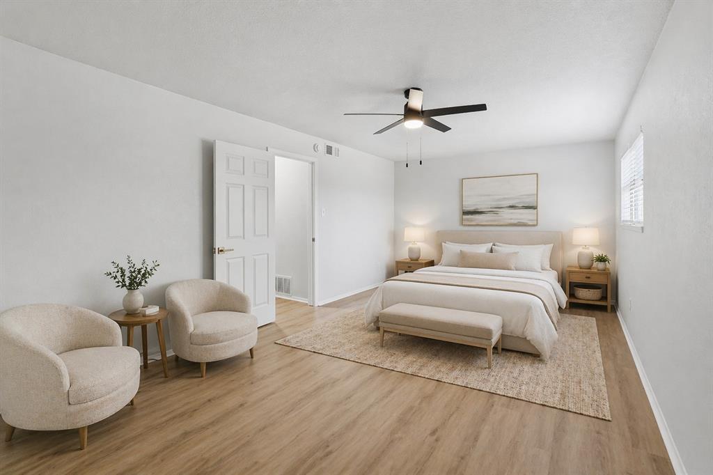 Spacious interior featuring wood-finish flooring, a ceiling fan with integrated lighting, and a six-panel interior door