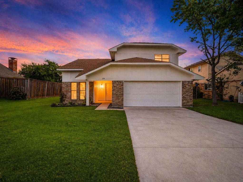 Two-story residence featuring a multi-material facade of brick and siding, a wide concrete driveway, an attached garage, and a sodded front lawn Two-story residence featuring a multi-material facade of brick and siding, a wide concrete driveway, an attached garage, and a sodded front lawn