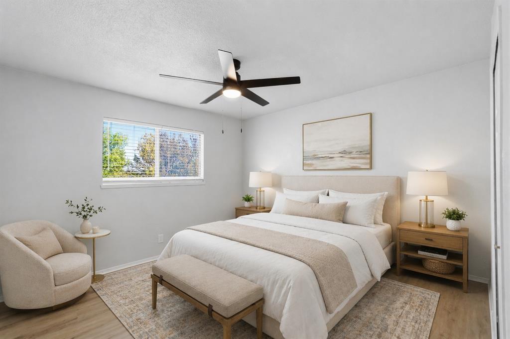 Bedroom featuring wood-finish flooring, a matte black ceiling fan with integrated lighting, and a large horizontal window with slatted blinds